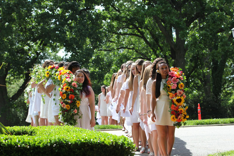 Sophomores dressed in white and holding the daisy chains