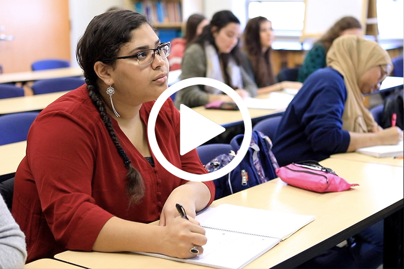 Click on image of female student in Red Sweater in class lecture to watch video in modal