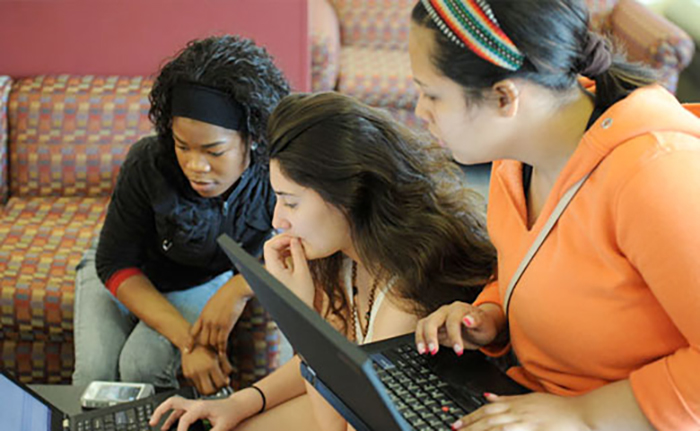 three female students looking at a laptop screen