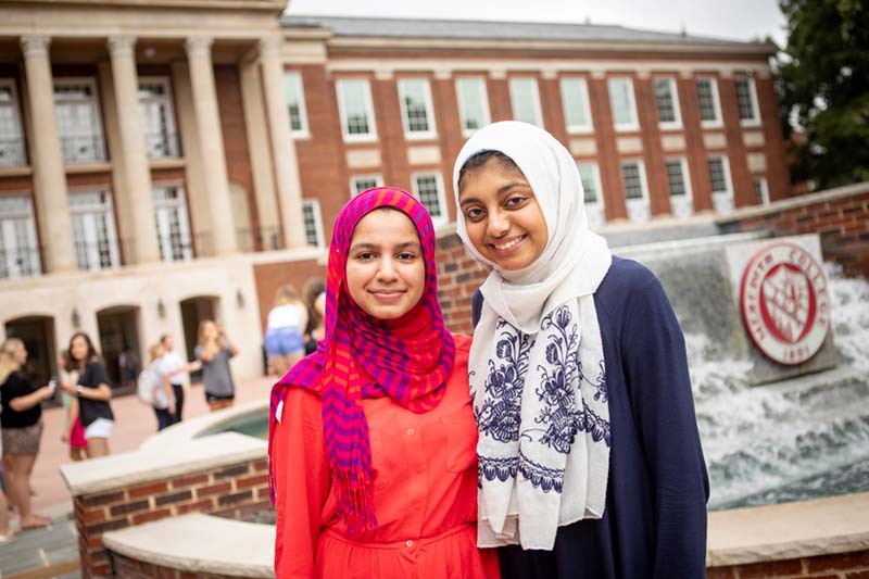 Two Students wearing colorful hijabs smiling in front of Beam Fountain