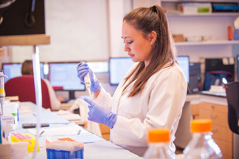 A Meredith student in a white lab coat in a research lab.