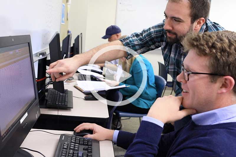 Click on Image of male students looking at Computer screen to play video in modal