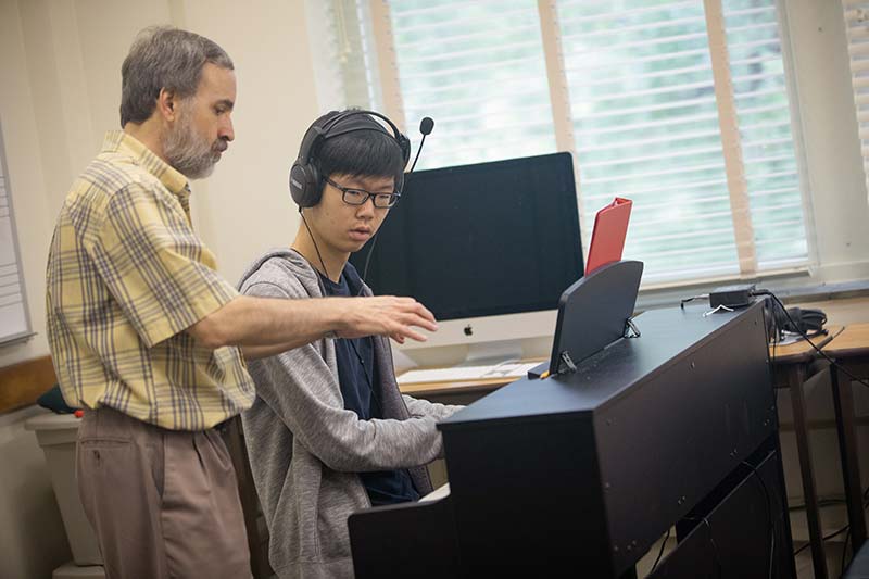 A student works with a professor during a piano lesson.