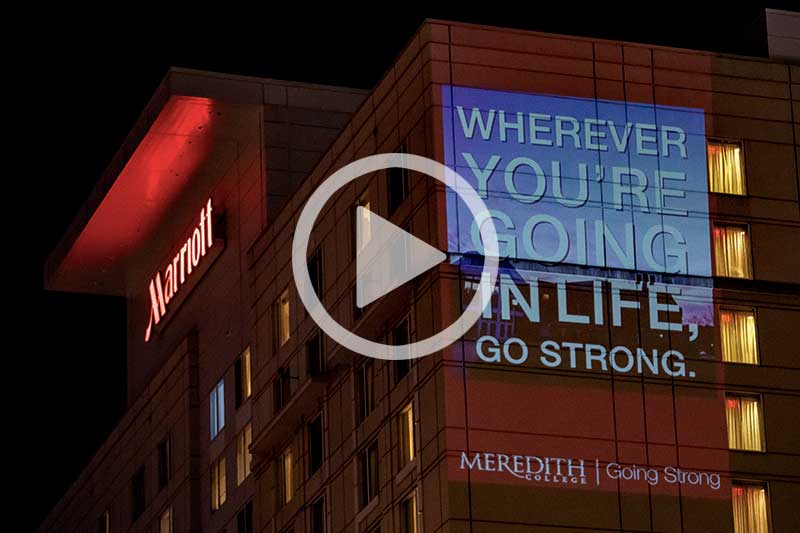 click image of building lit up at night with Meredith College projected on side to watch video in modal