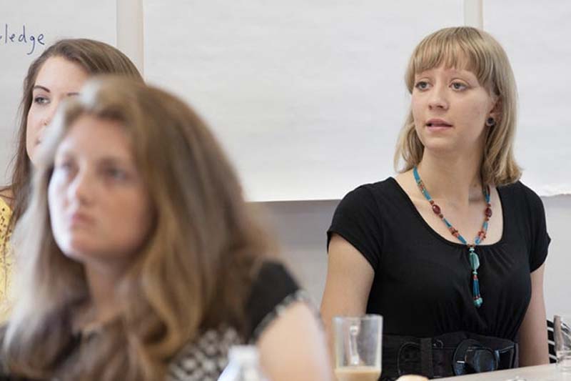 click image of female students seated in row for a short distance to watch Meredith College Teaching Fellows video in modal