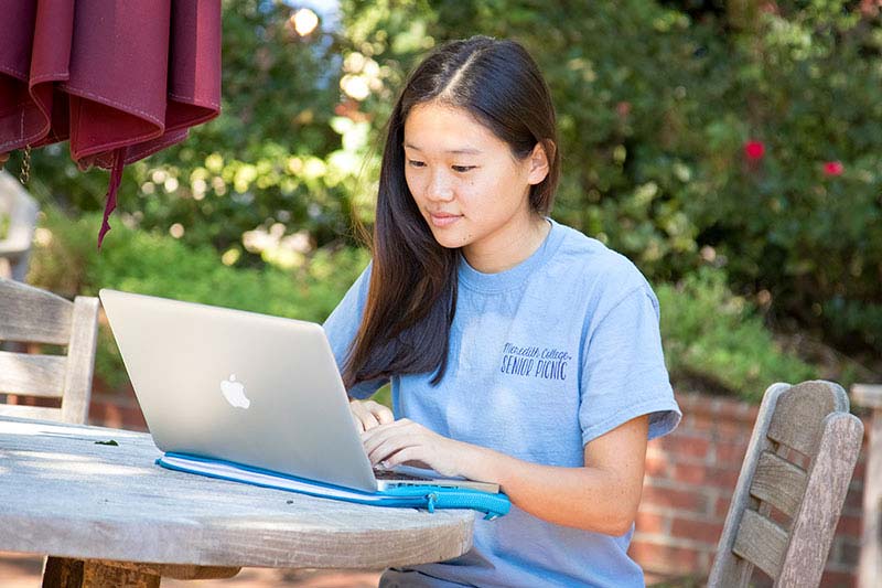 Woman wearing blue shirt looking at an open laptop