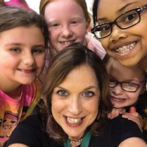 Anne Carroll Ezzelle surrounded by children smiling.