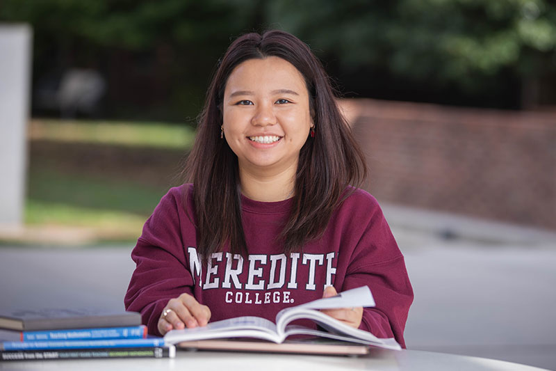 Meredith Student flipping through book and smiling