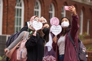 Students taking a selfie holding "Happy Birthday, Meredith!" signs.