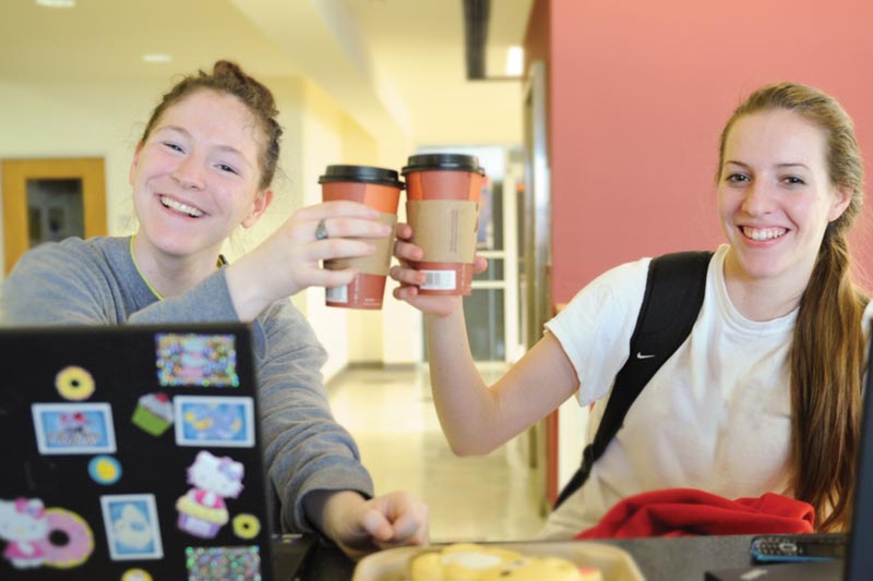 Two students clink coffee cups.