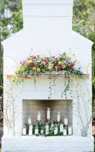 A white fireplace outside with decorations.