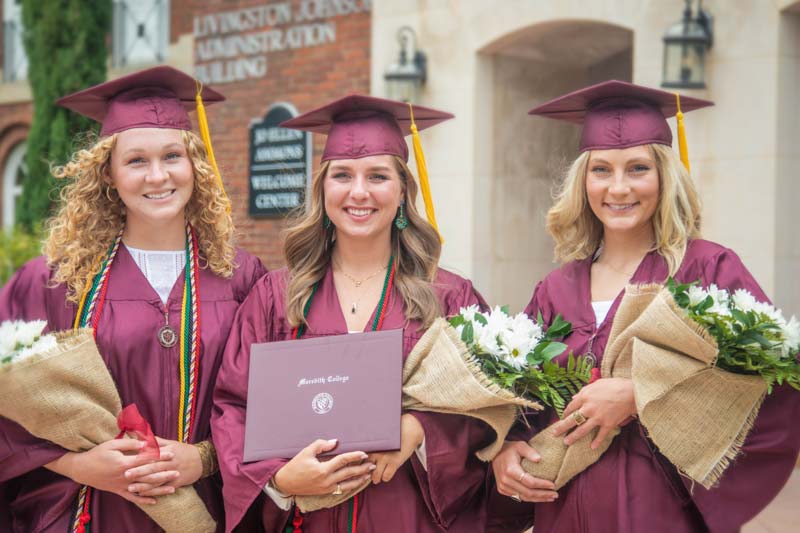 Lacrosse seniors Olivia Blake, Caroline Butler, and Maya Flake at a special commencement ceremony, wearing caps and gowns.