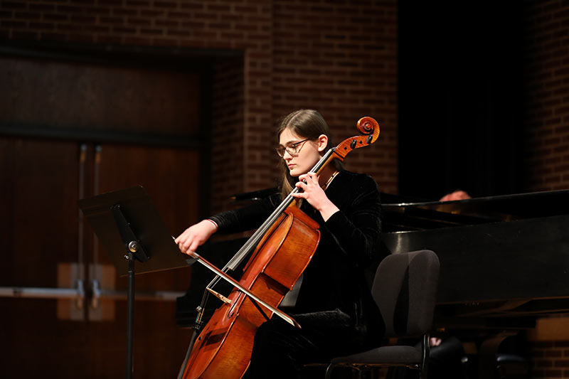 A student plays the cello at a concert.