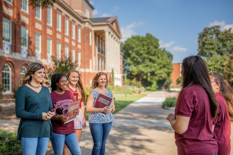Four students in front of Johnson Hall on the Meredith Admissions Tour with tour guides.