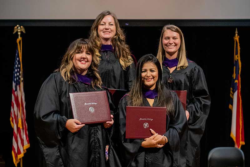 Four graduates with a degree of master of arts in criminal justice.
