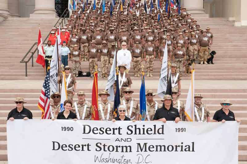 Members of the military holding a sign in DC that says Desert Shield and Desert Storm Memorial 1990 and 1991.