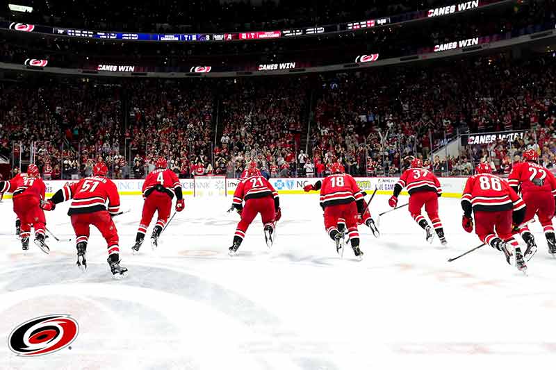 The Carolina Hurricanes team members skating on the ice to a large crowd.