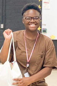 New teacher in classroom holding tote bag gift from Meredith