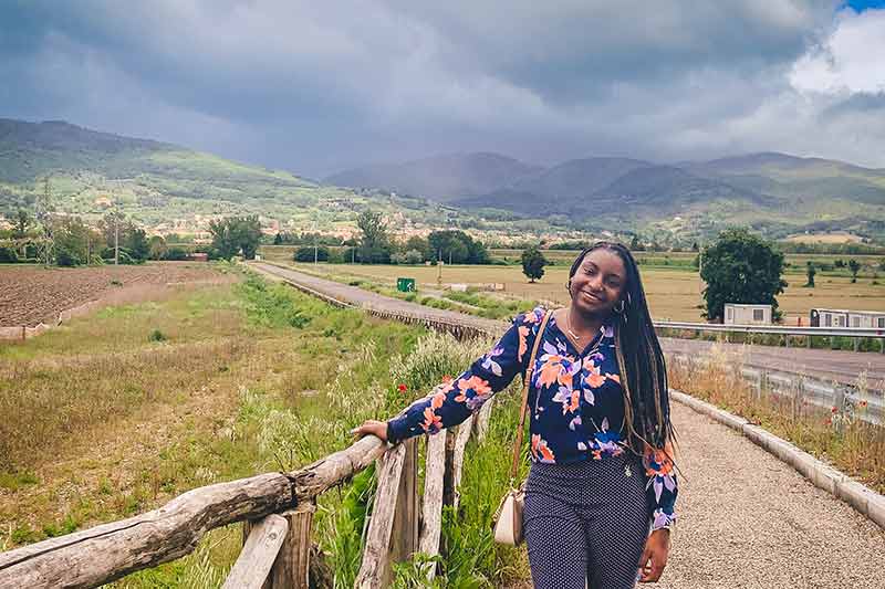 Amirah Clark posing for a photo in front of a beautiful country scene on her study abroad.