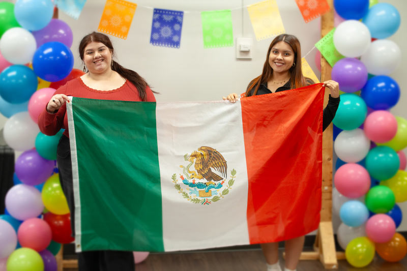 Two Meredith students holding a Mexican flag for an event hosted by Angeles Latines