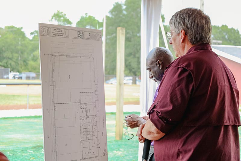 People observe the blueprints for the new athletic complex.