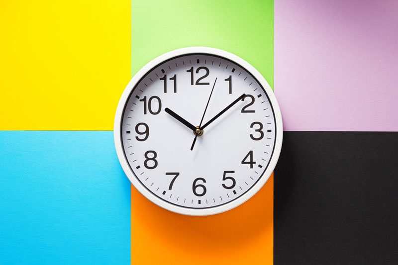 Clock on Yellow, Green, Pink, Blue, Orange and Black Square tiled wall.